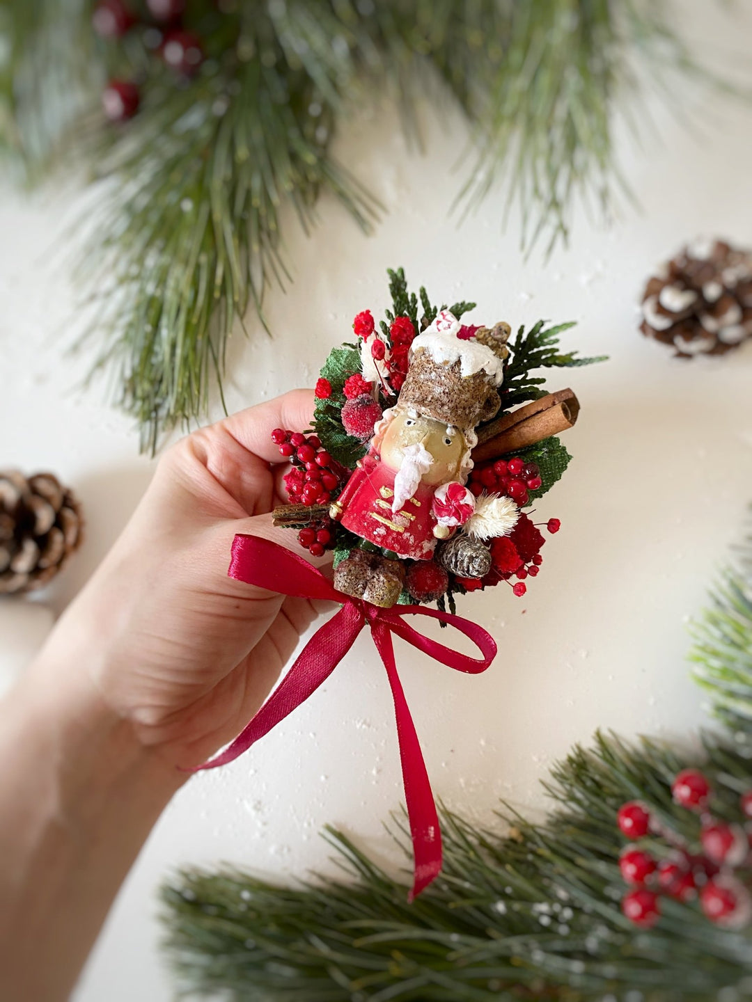 Limited  edition handmade Nutcracker Christmas brooch with red berries, pine cones, cinnamon and a bow for coats, hats and scarves