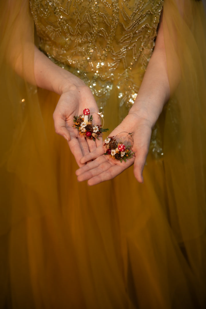 A close-up of a person in a shimmering gold sequined dress holding circle dangle earrings  in their hands against a soft, out-of-focus gold background.