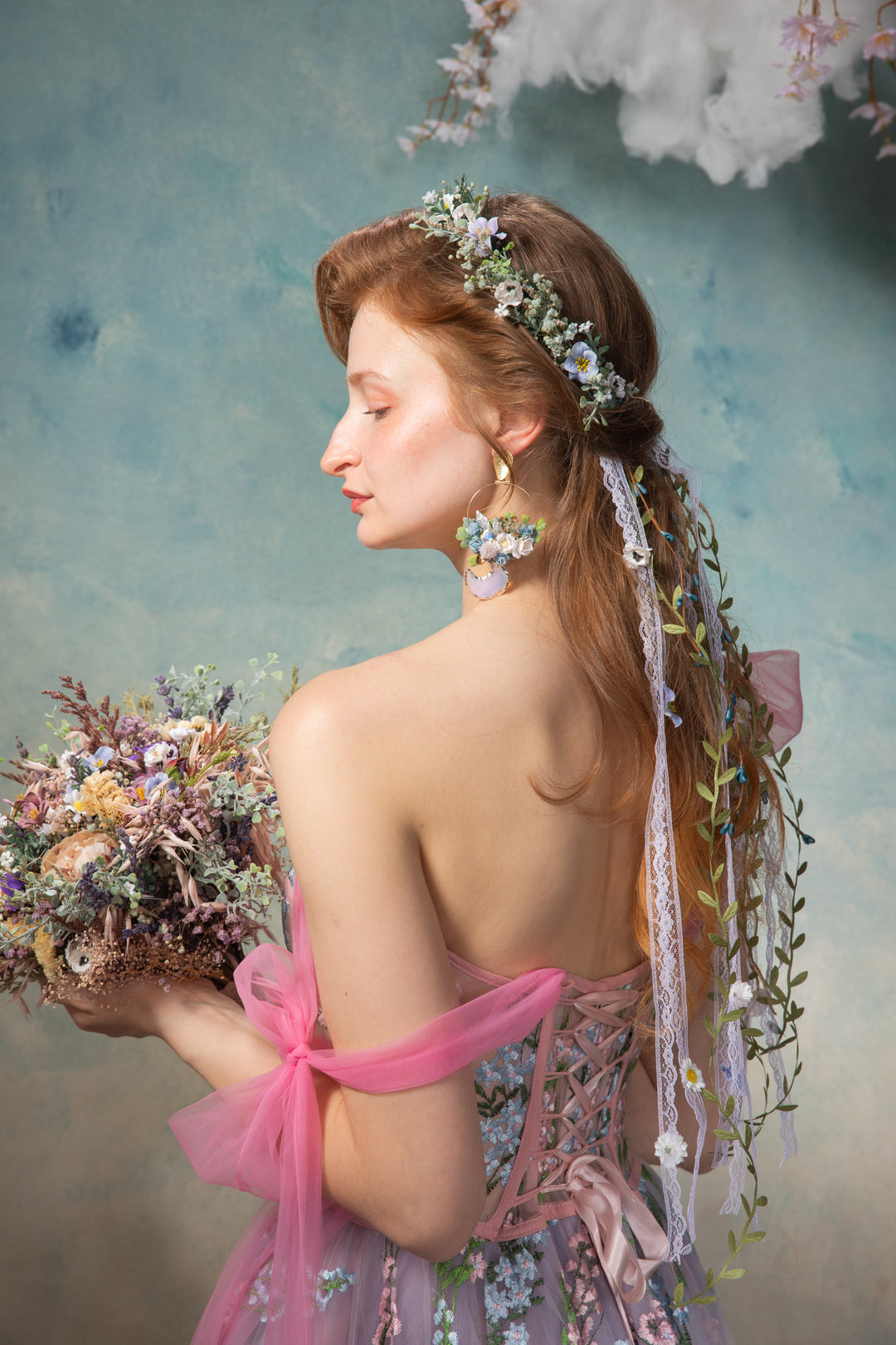 Woman with floral hair and bouquet against a soft, cloud-like background