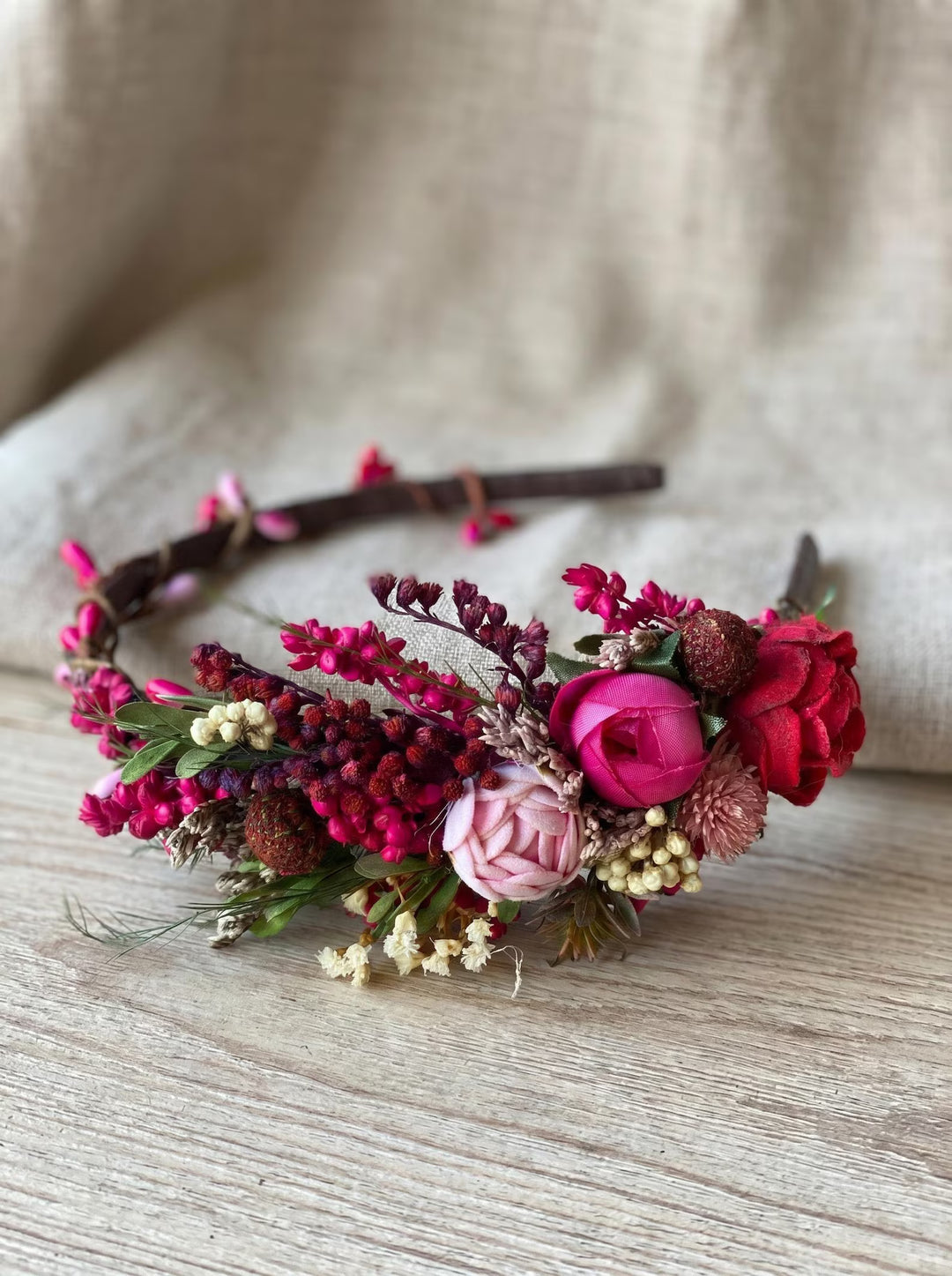 Floral headband with pink and red flowers on a wooden surface