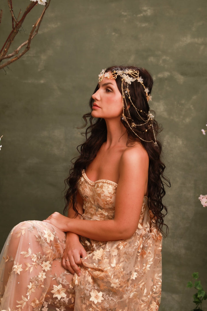 Woman in a floral dress with a headpiece against a green background