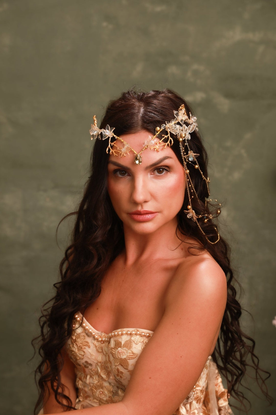 Woman wearing a gold headpiece against a green background