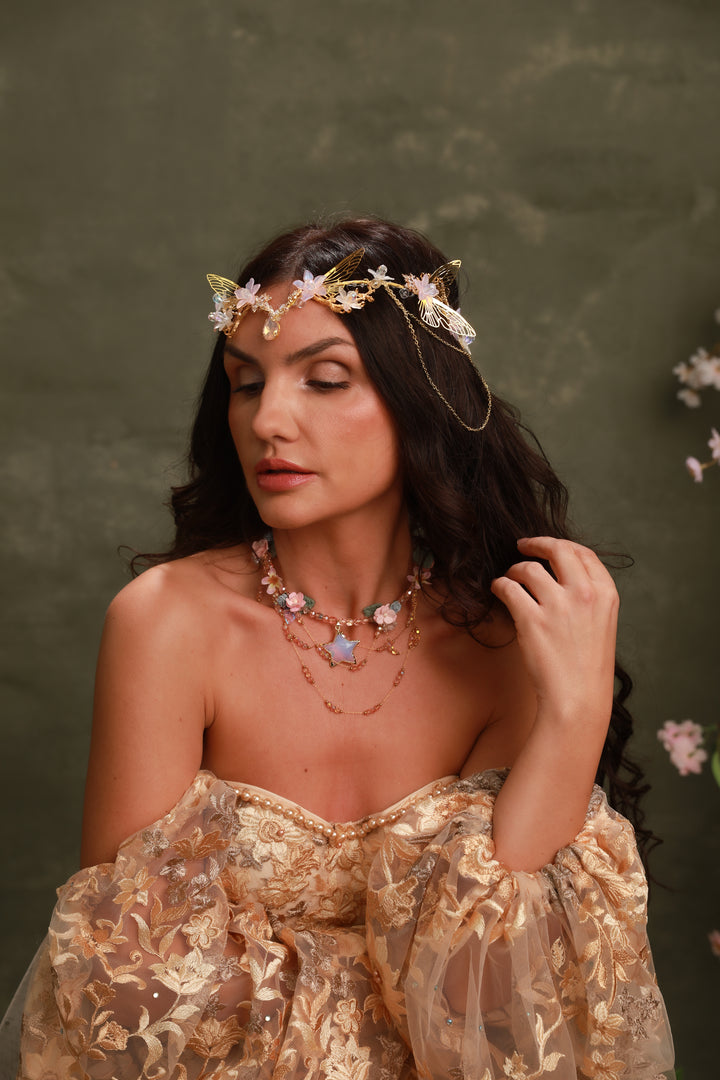 Woman wearing a floral headpiece and gold dress against a green background