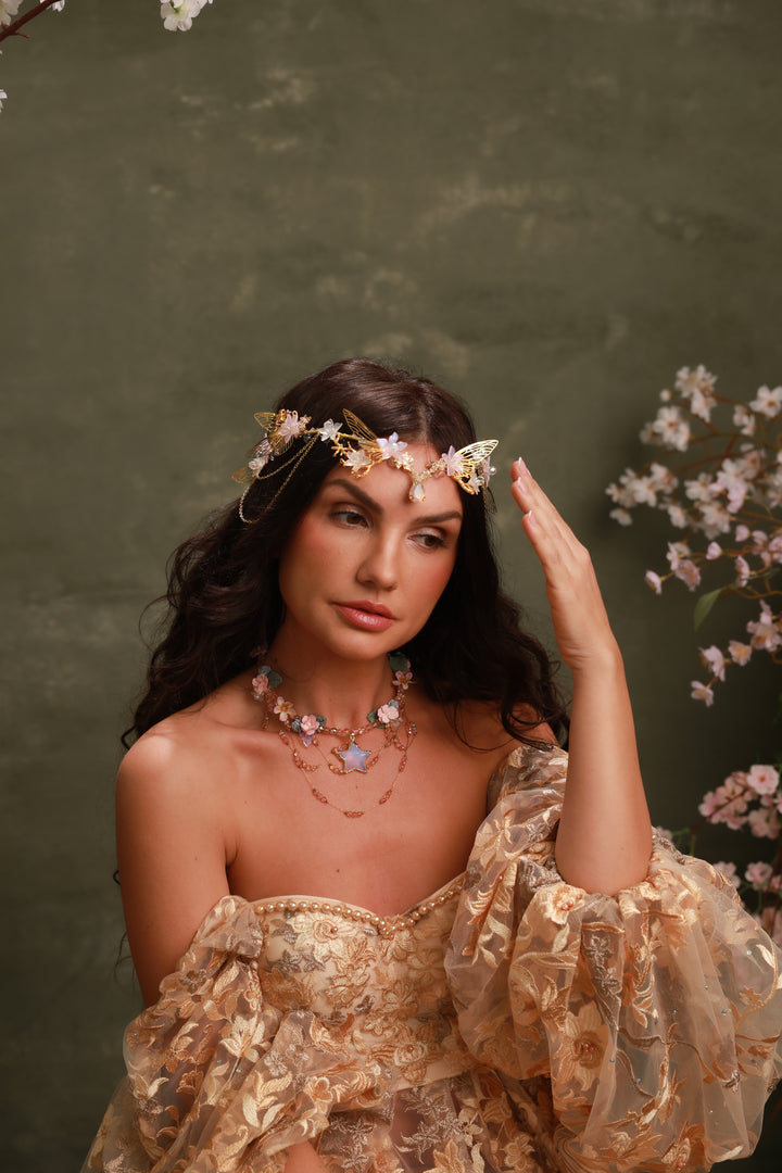 Woman in a gold dress with floral headpiece against a green background