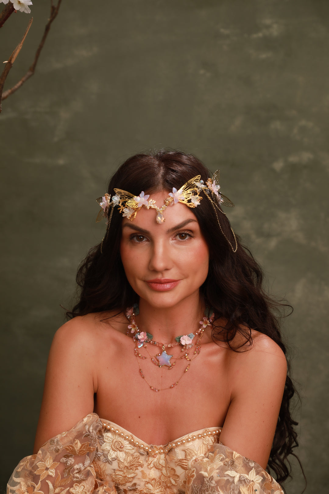 Woman wearing a floral butterfly tiara and gold dress against a green background