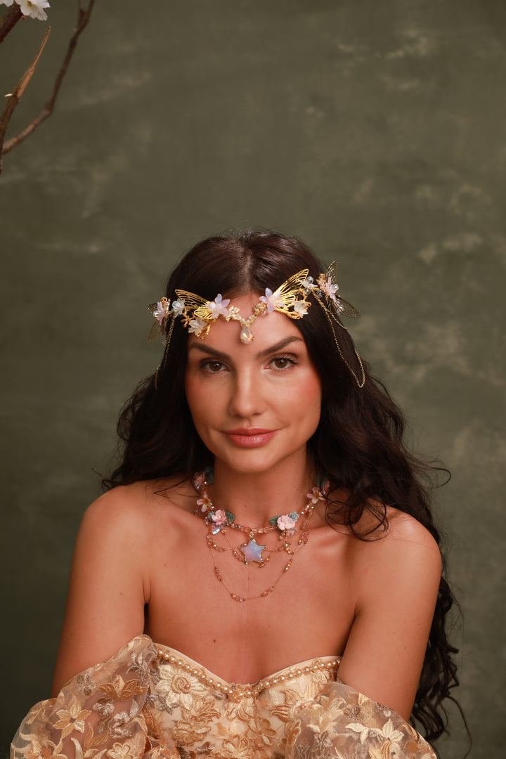 Woman wearing a floral butterfly tiara and gold dress against a green background