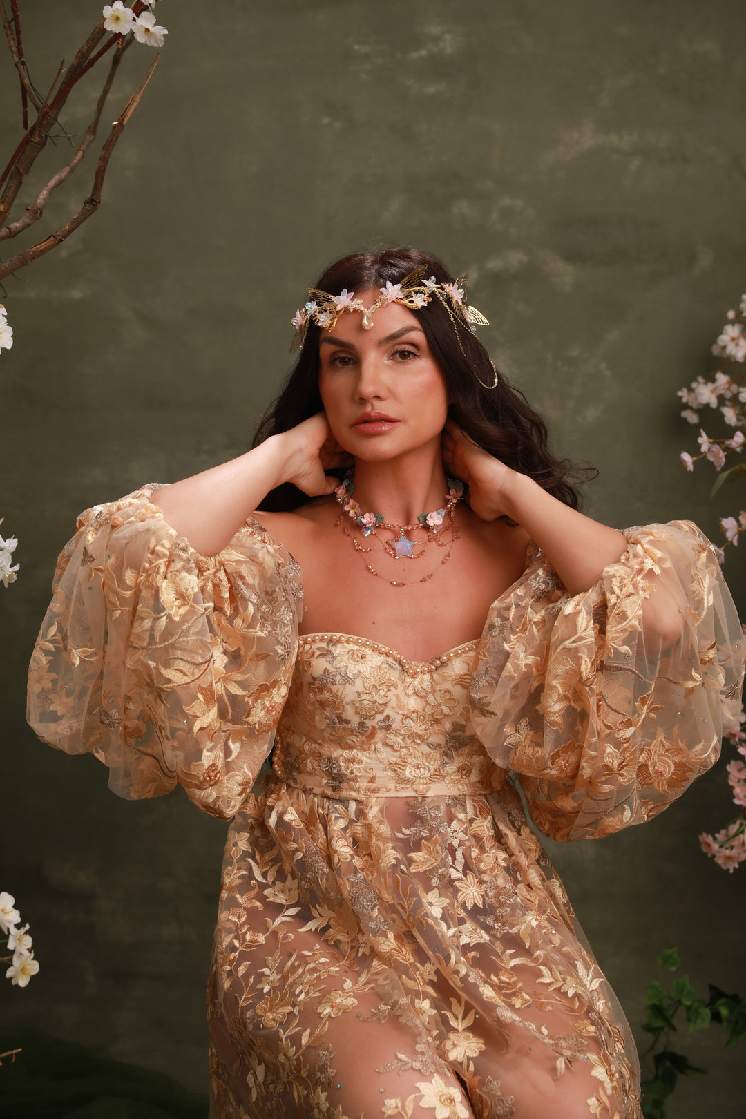 Woman in a gold dress with floral headpiece against a green background