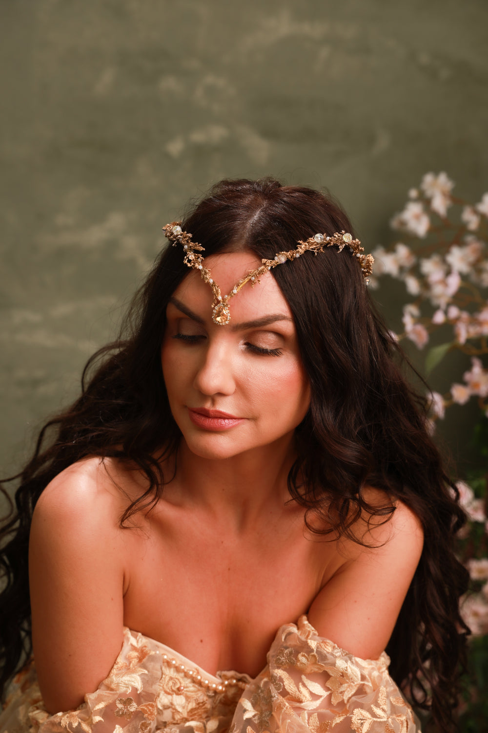 Woman wearing a gold tiara with crystals with a floral background