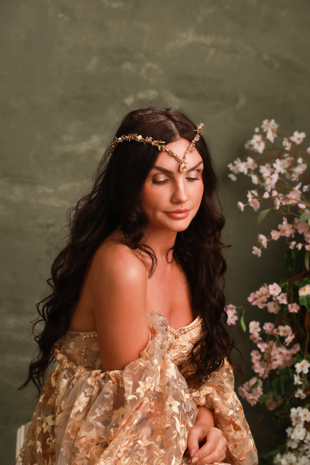 Woman in a floral dress with a golfen tiara against a green background with flowers