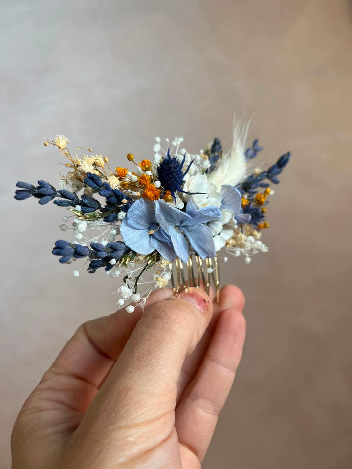 Dusty blue hair comb with  textile anemones in white, preserved powder blue hydrangea, lavender, navy thistles, gypsophila, and warm ochre dried florals, all nestled into a lush, textured arrangement that feels effortlessly natural and deeply romantic