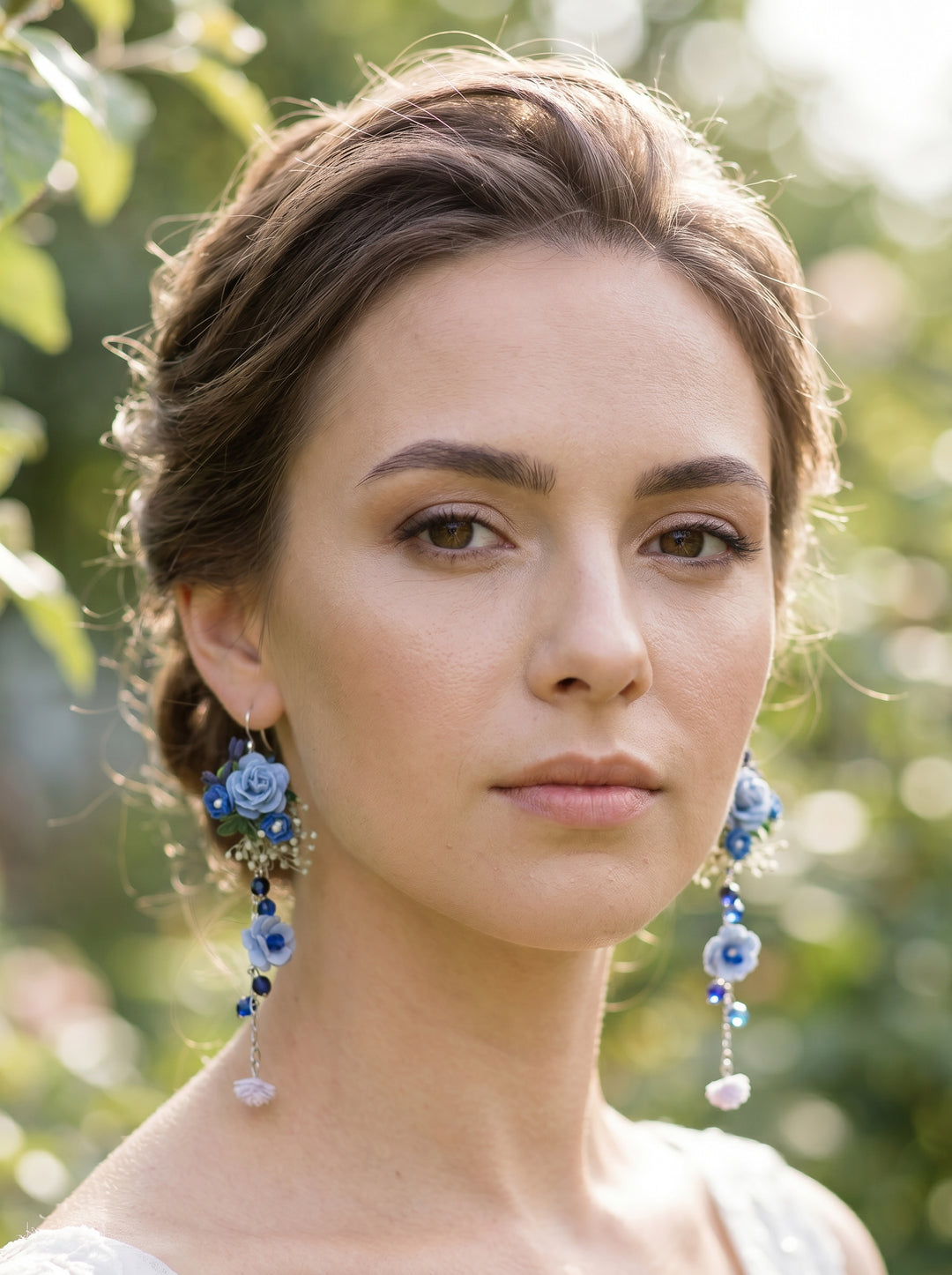 Woman wearing blue floral earrings with dusty blue roses, chain and beads