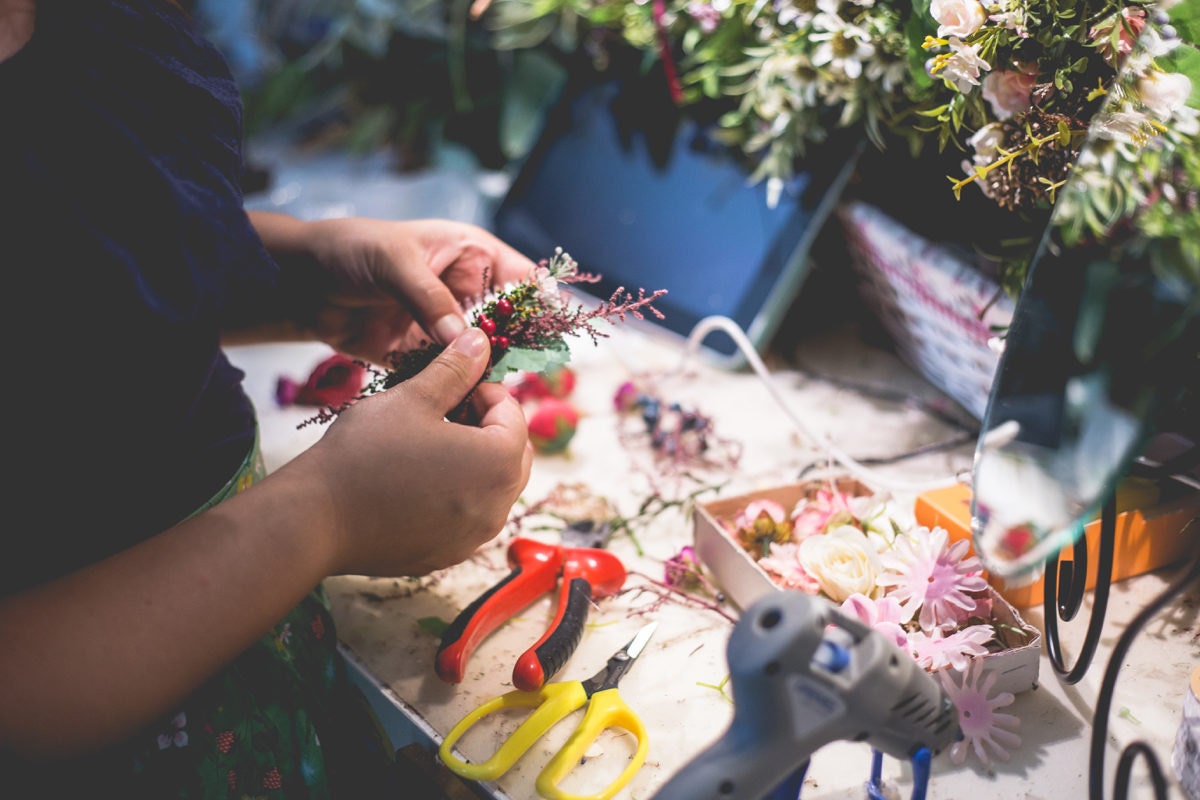 Person crafting with flowers and tools on a table
