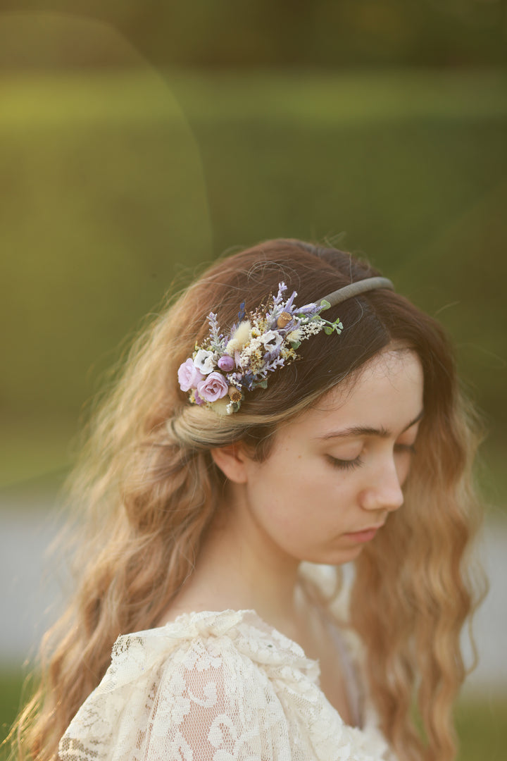 Woman wearing a floral headband in purple tones  with a blurred natural background