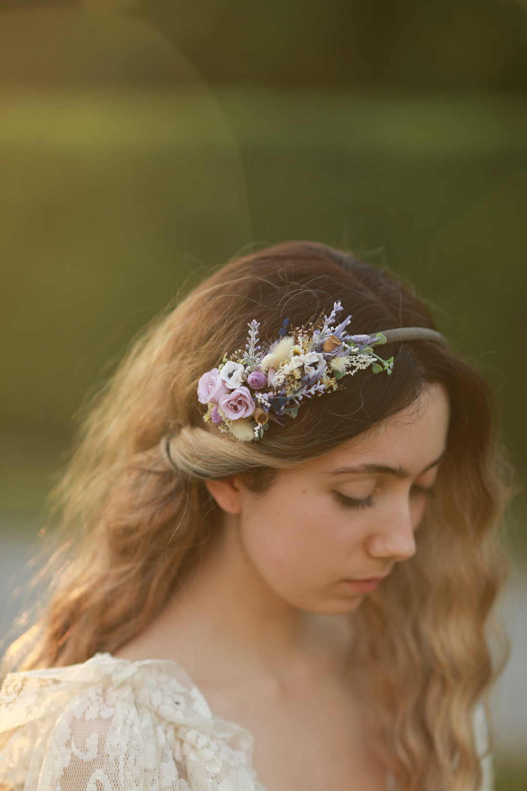 Woman wearing a floral headband in purple and cream tones with a blurred natural background