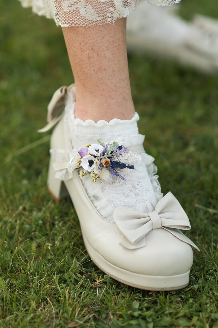 White shoe with decorative bow and floral shoe clips on grass