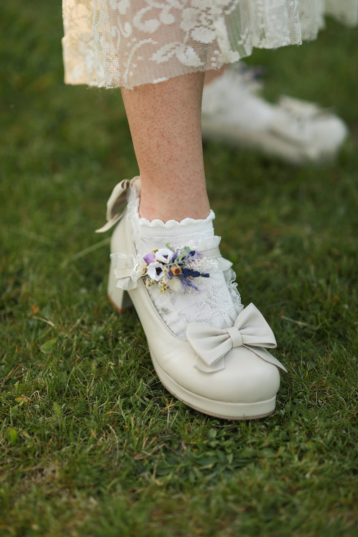 White lace-up shoes with decorative flowers on a grassy background