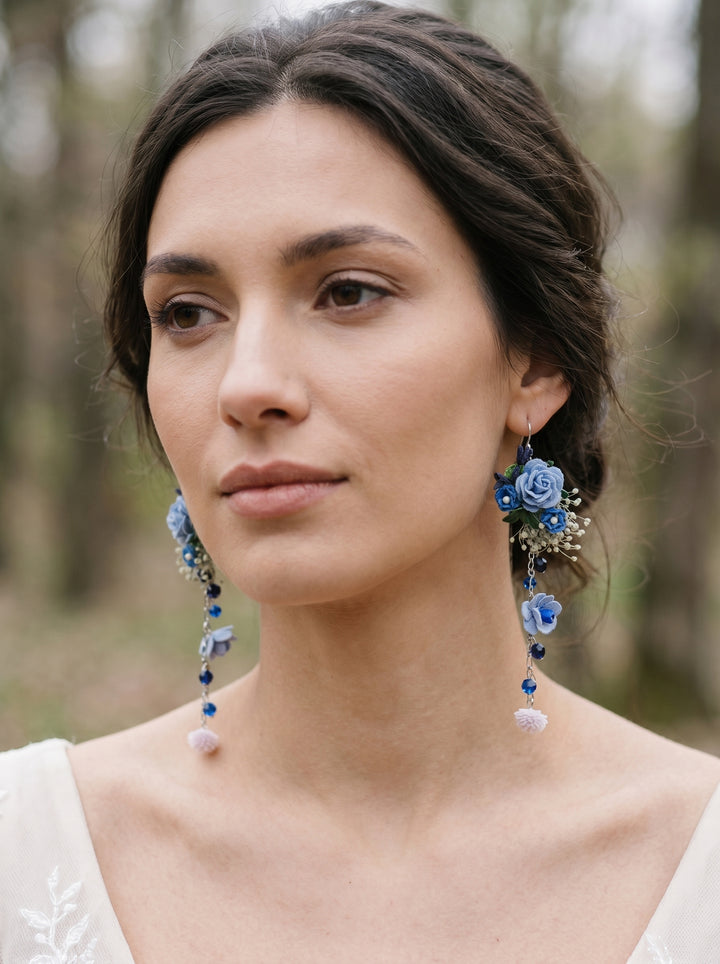 Woman wearing blue floral earrings with a blurred natural background