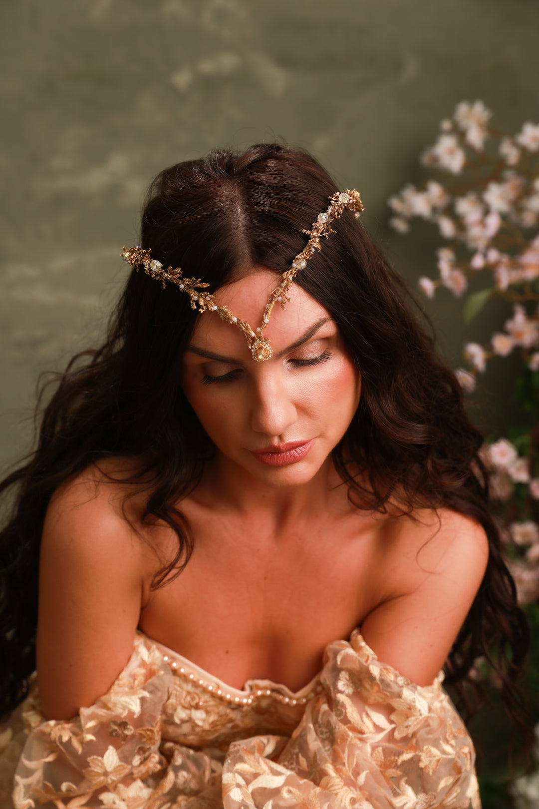 Woman wearing a gold headpiece with a floral background