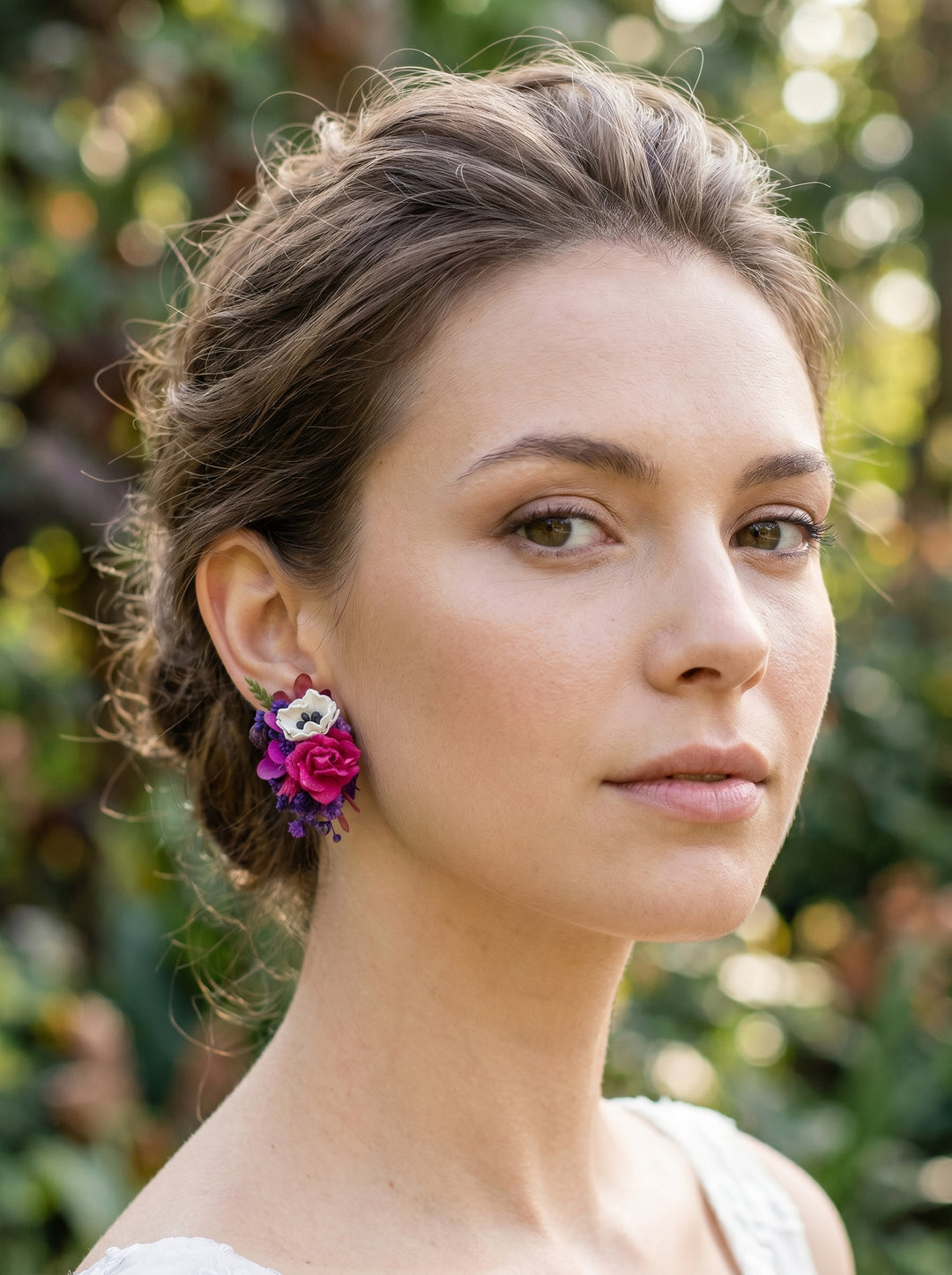 Woman wearing floral earrings with a blurred green background