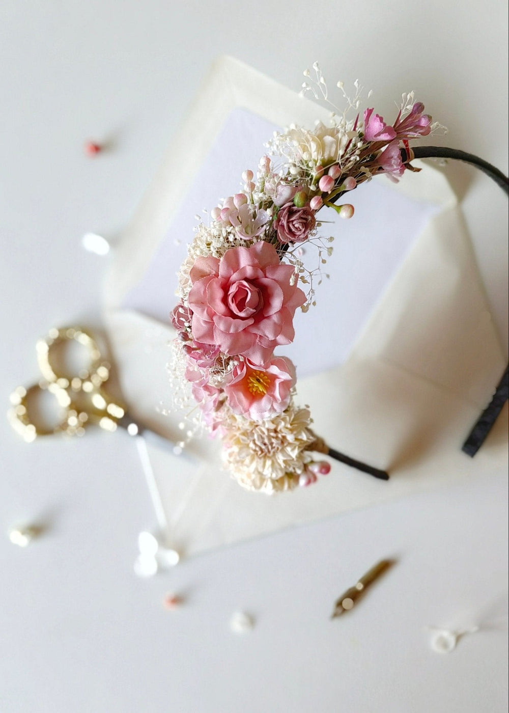 Floral headband with pink flowers on a white surface