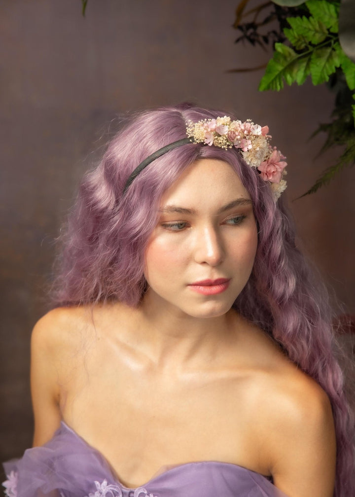 Woman with purple hair and floral headband against a brown background