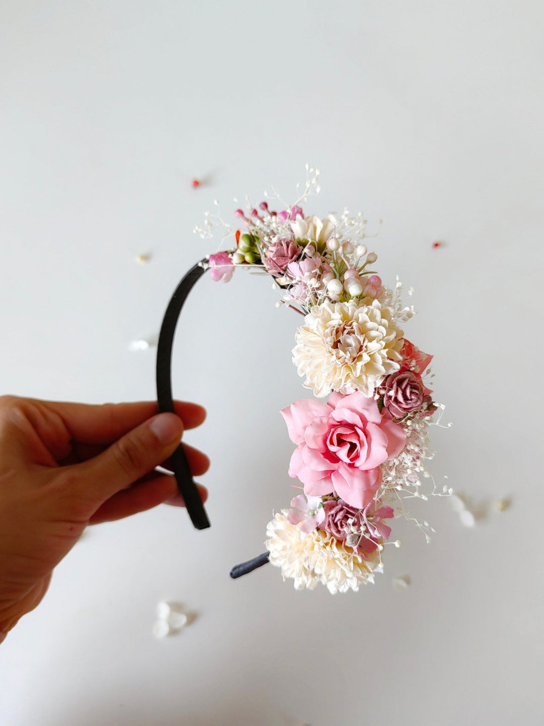 Floral headband held by a hand on a light background