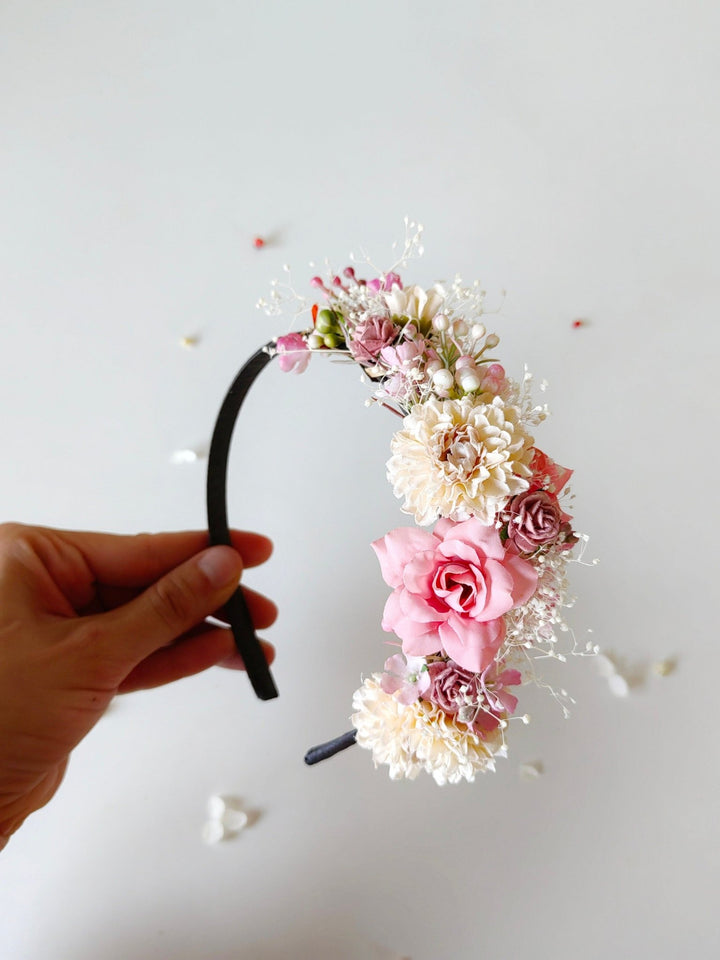 Floral headband held by a hand on a light background