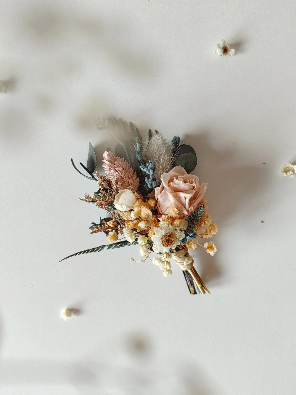 Floral boutonniere with pink roses and dried elements on a light background