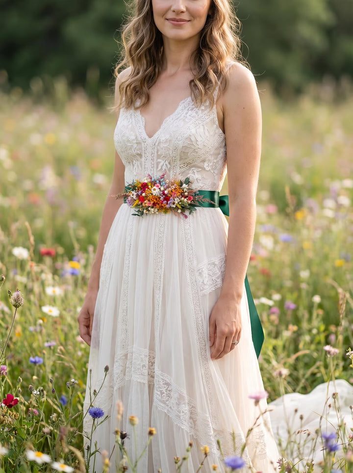 Woman in a white dress with a floral belt standing in a field of wildflowers.
