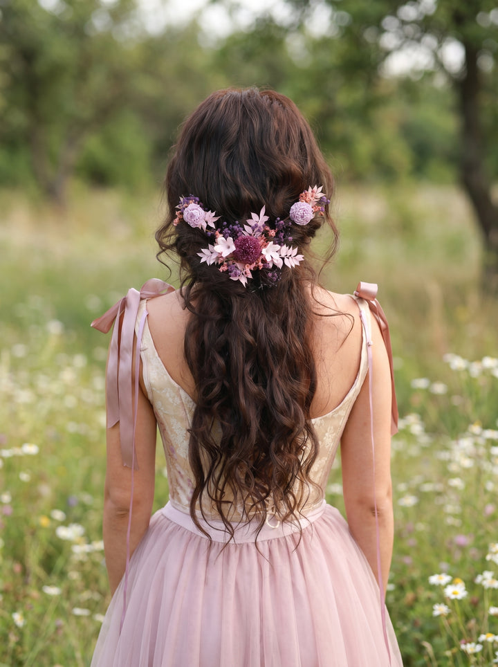 Woman with floral preserved purple hair vine and pink dress standing in a field