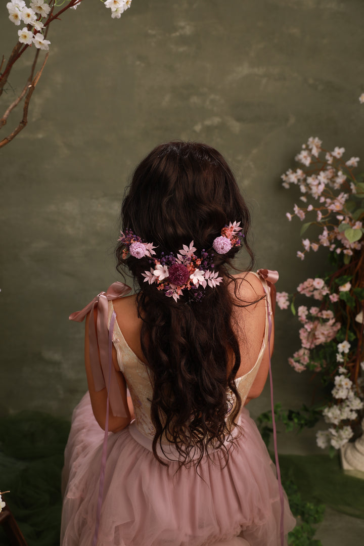 Woman with floral hair accessory in a pink dress against a green background
