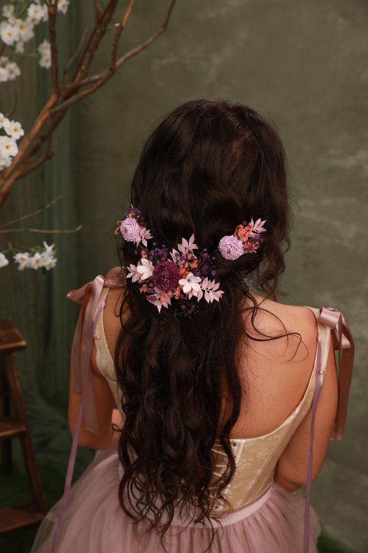 Woman with floral hairpiece and pink dress against a green background