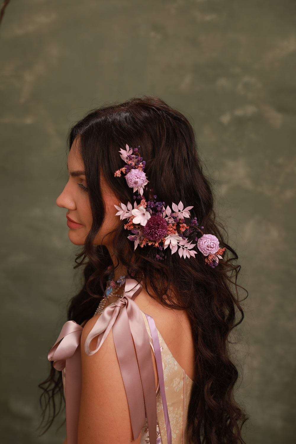 Woman with floral hairpiece and ribbons against a green background