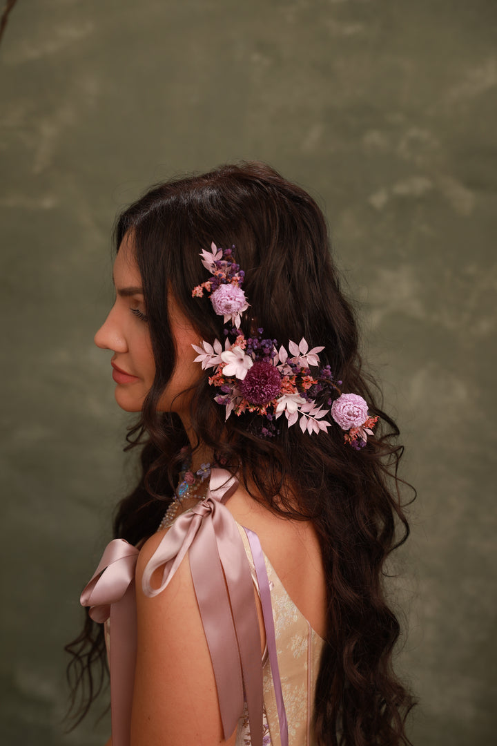 Woman with floral hairpiece and ribbons against a green background