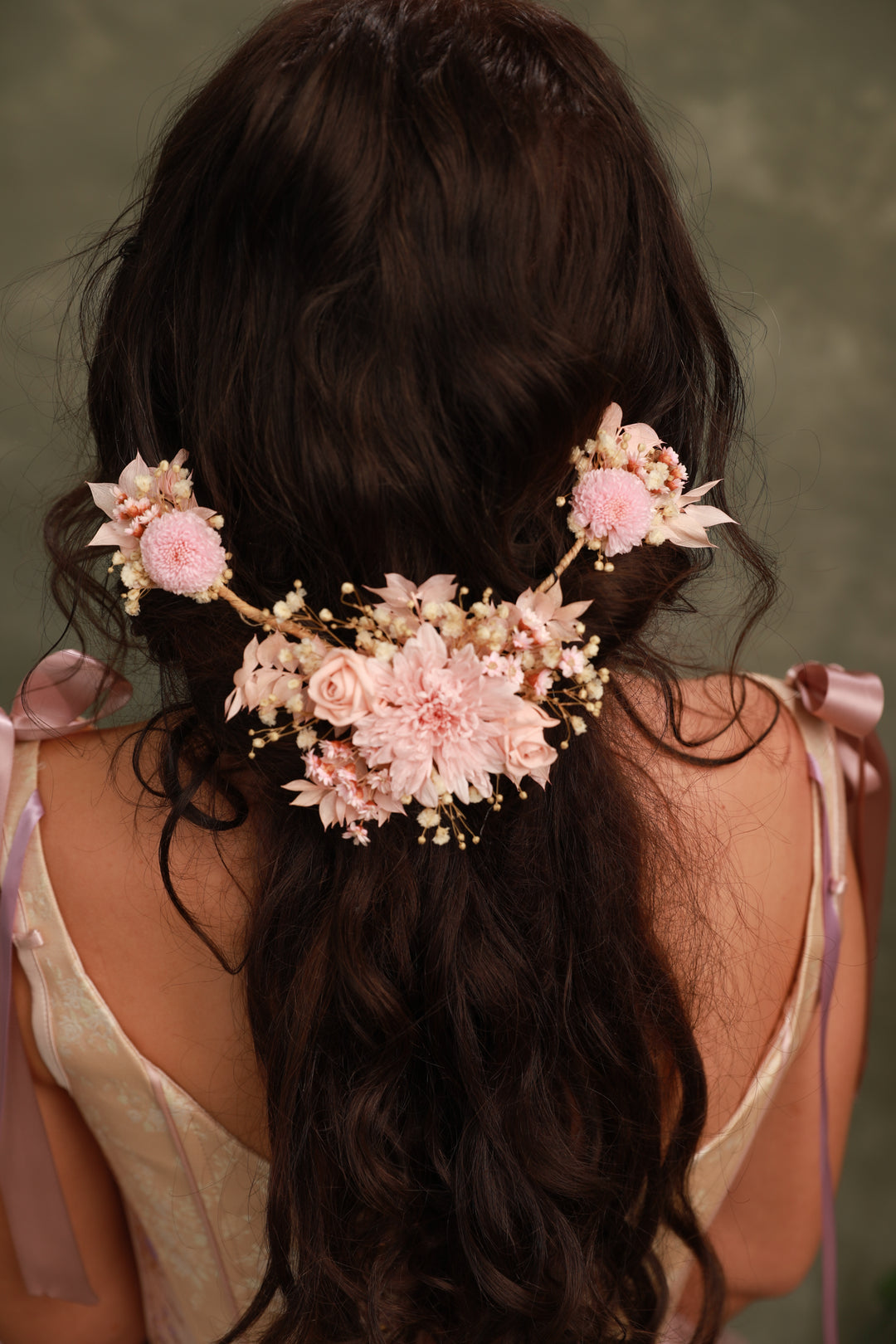 Woman with braided hair adorned with pink floral hair accessories against a neutral background
