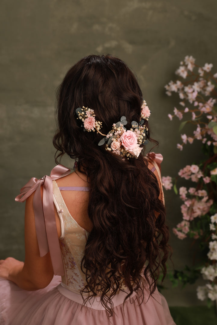 Woman with floral hair accessory and pink dress against a green background