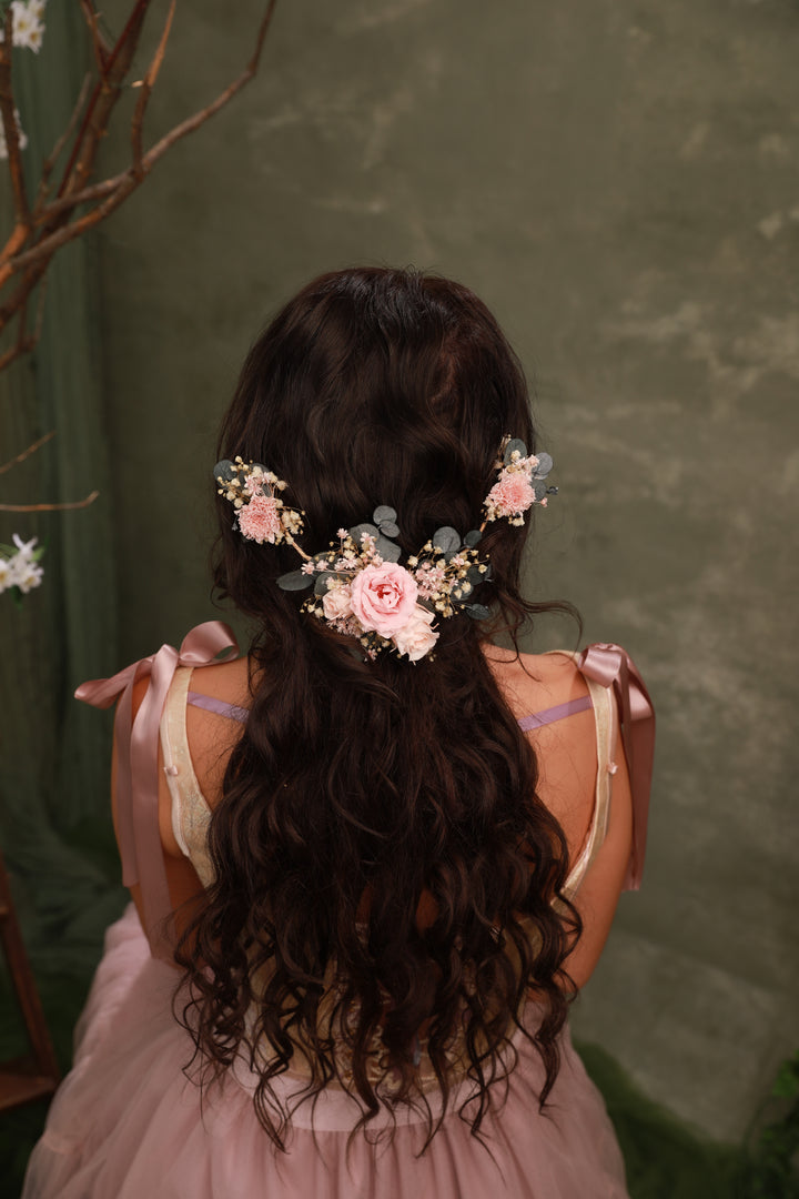 Person with floral hair accessory and pink dress against a green background