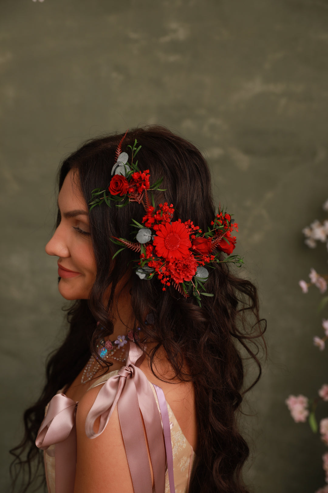 Woman with floral headpiece and ribbons against a textured green background