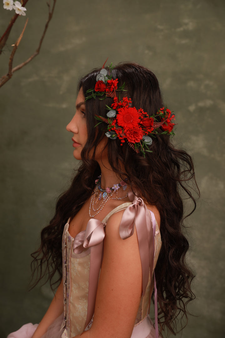Woman with floral headpiece and ribbons in hair against a green background