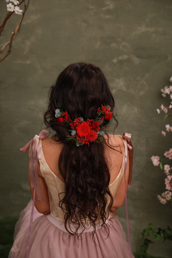 Woman with floral hairpiece and pink dress against a green background
