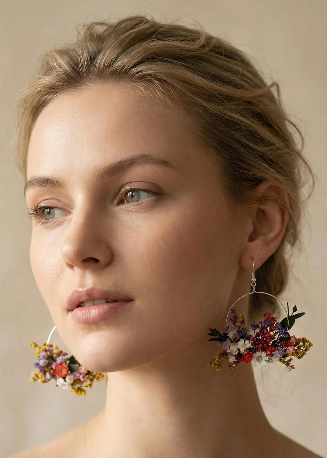 Woman wearing floral hoop earrings against a neutral background