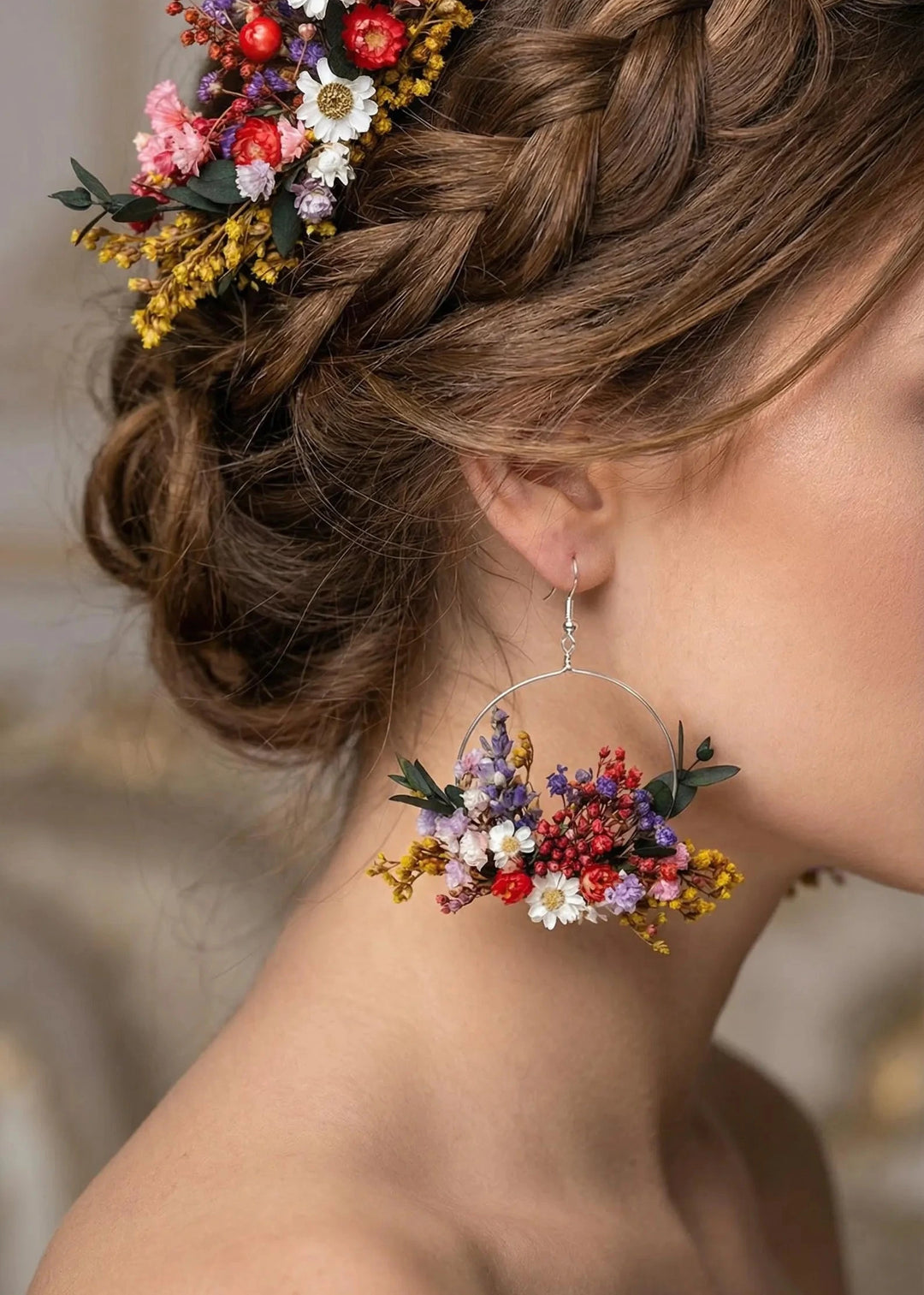 Woman with braided hair adorned with colorful flowers, wearing matching floral earrings.