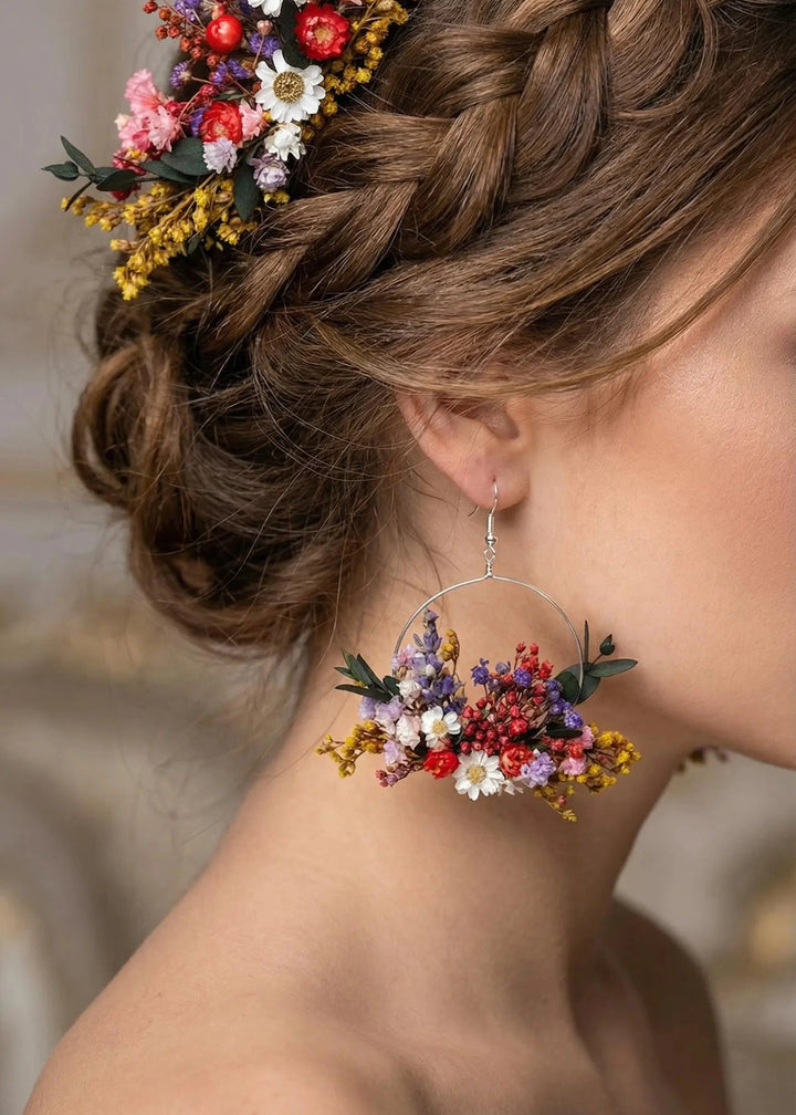 Woman with braided hair adorned with colorful flowers, wearing matching floral earrings.