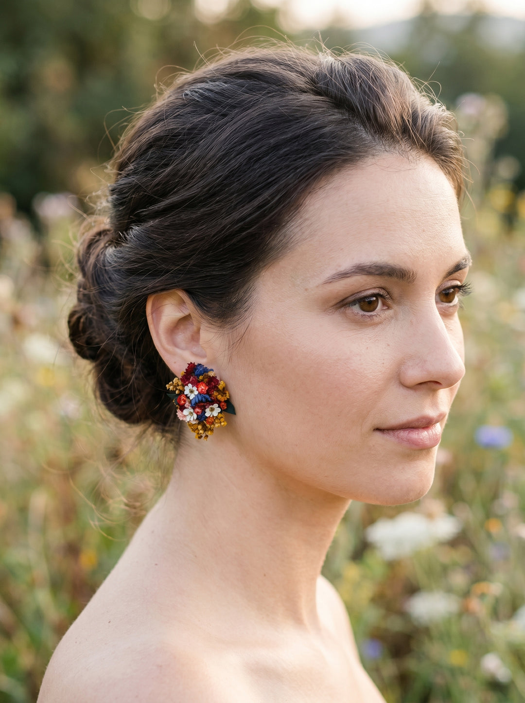 Woman with styled hair and colorful earrings against a natural background
