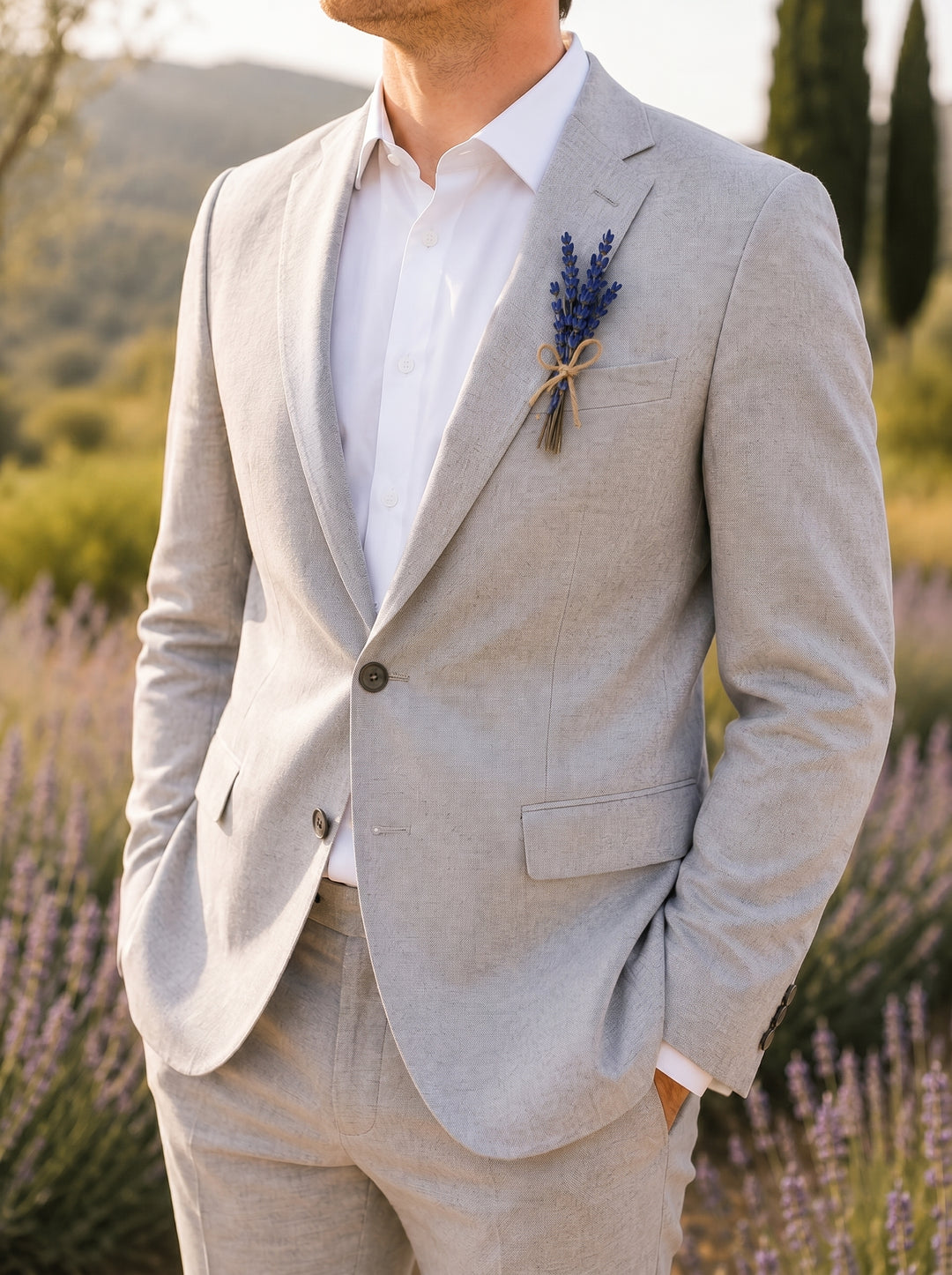 Man in a light gray suit with a lavender boutonniere standing in a field of lavender.