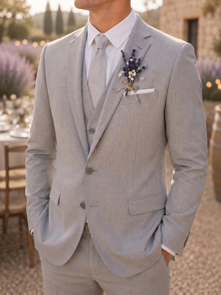 Man wearing a light gray suit with a boutonniere in an outdoor setting with lavender.