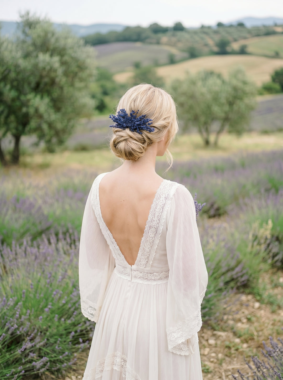 Woman in a white dress with an open back standing in a lavender field.