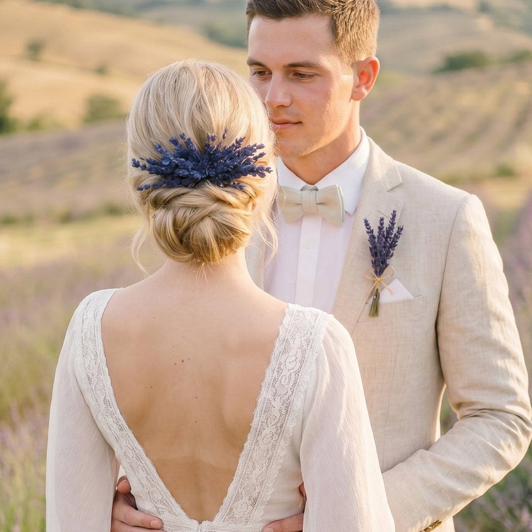 Man and woman standing in a lavender field, with the woman wearing a white dress and the man in a beige suit.