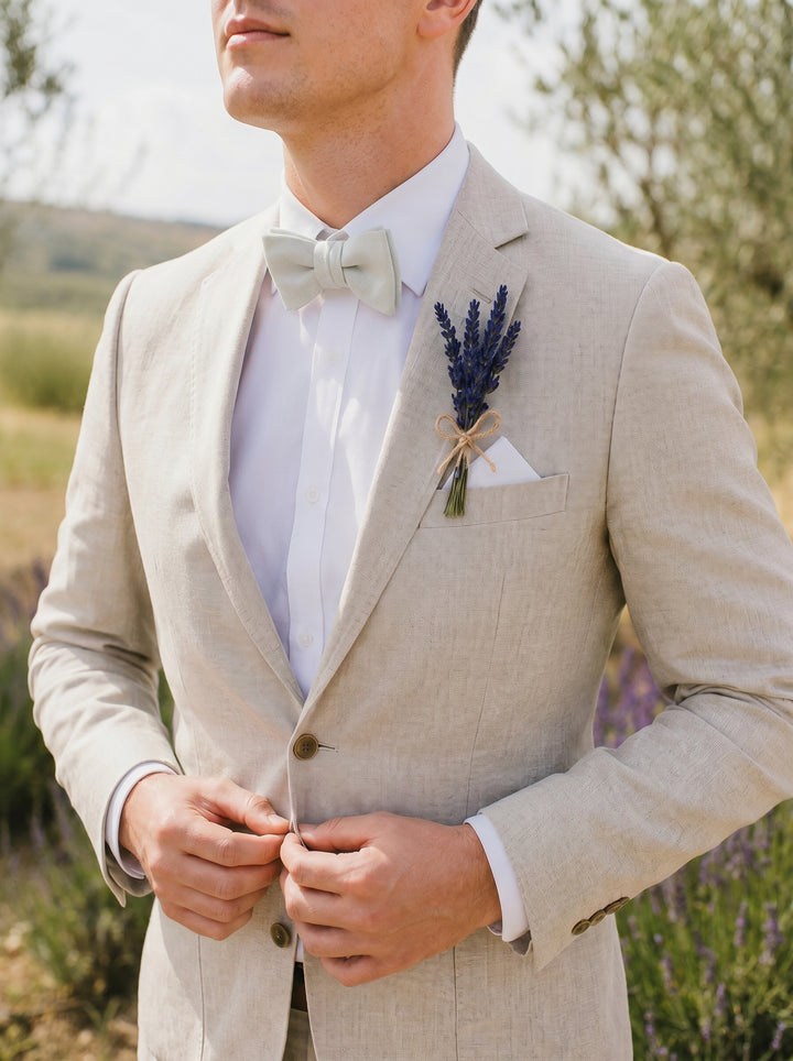Man in a beige suit with a lavender boutonniere in the background