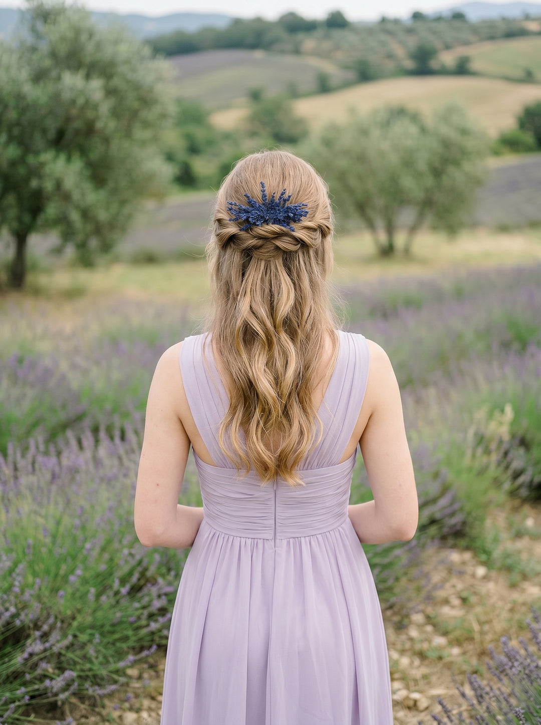 Woman in a lavender dress with a floral headpiece standing in a field of lavender.